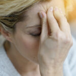 Migräne: Eine Frau mit geschlossenen Augen drück die Finger einer Hand an die Stirn.